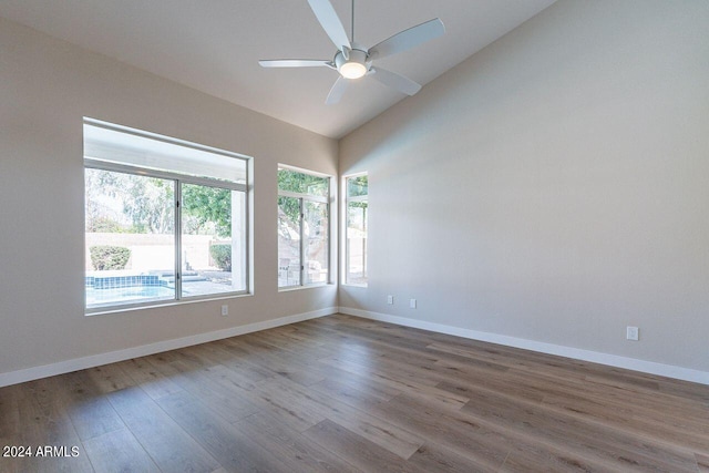 spare room featuring ceiling fan, lofted ceiling, and light wood-type flooring