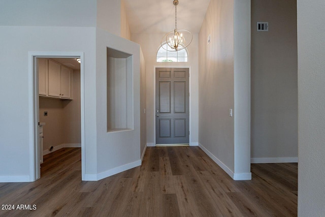 foyer entrance featuring hardwood / wood-style flooring, a notable chandelier, and a towering ceiling