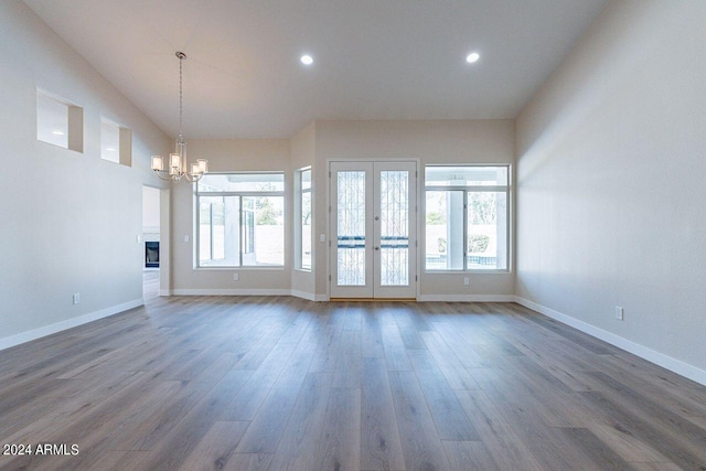 unfurnished living room featuring dark hardwood / wood-style floors, lofted ceiling, and a chandelier