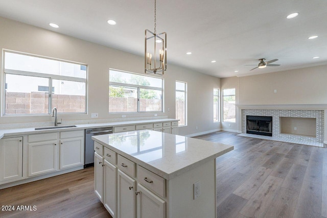 kitchen with white cabinetry, sink, stainless steel dishwasher, pendant lighting, and light wood-type flooring