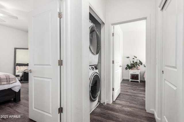 laundry area with dark wood-type flooring, a ceiling fan, and stacked washer / drying machine