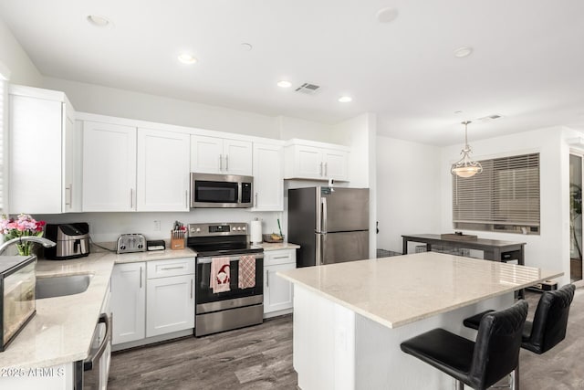 kitchen featuring white cabinets, appliances with stainless steel finishes, a kitchen island, and pendant lighting