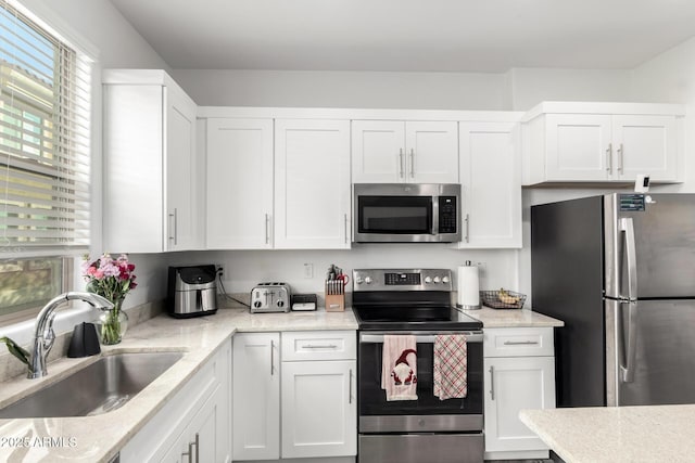 kitchen featuring appliances with stainless steel finishes, white cabinetry, and a sink