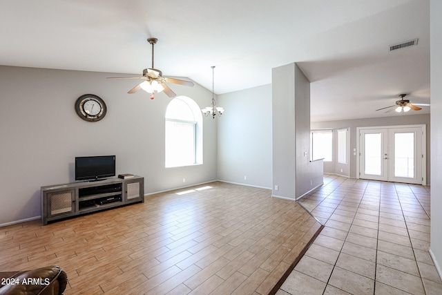 unfurnished living room with french doors, lofted ceiling, ceiling fan with notable chandelier, and a wealth of natural light