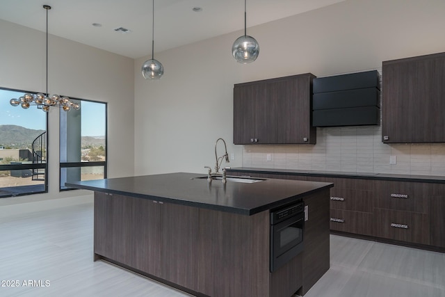 kitchen featuring hanging light fixtures, an island with sink, a mountain view, and sink