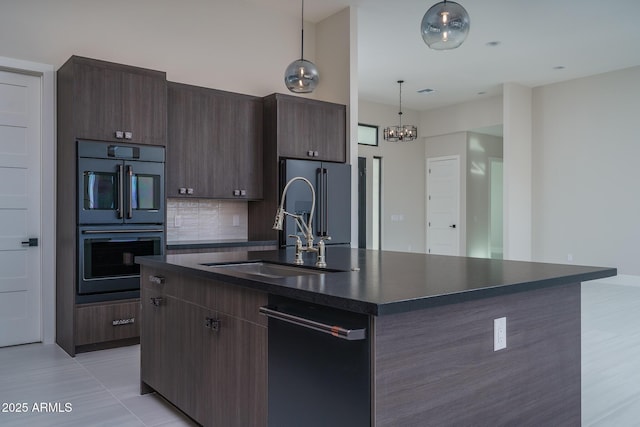 kitchen featuring pendant lighting, sink, a center island with sink, and multiple ovens