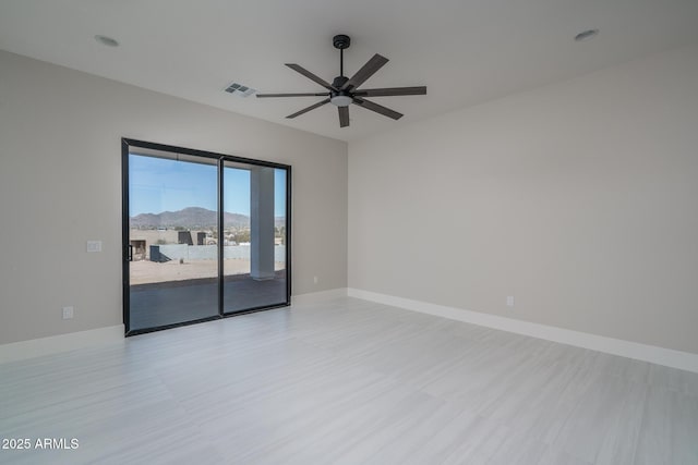 empty room featuring a mountain view and ceiling fan