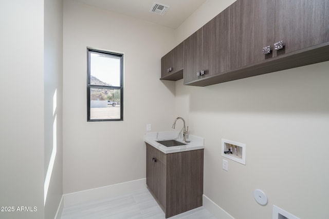 washroom with hookup for a washing machine, sink, cabinets, and hookup for a gas dryer