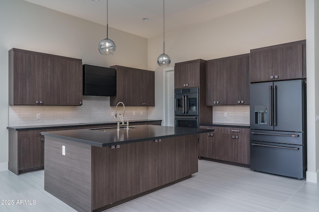 kitchen with high quality fridge, sink, hanging light fixtures, a kitchen island with sink, and dark brown cabinets