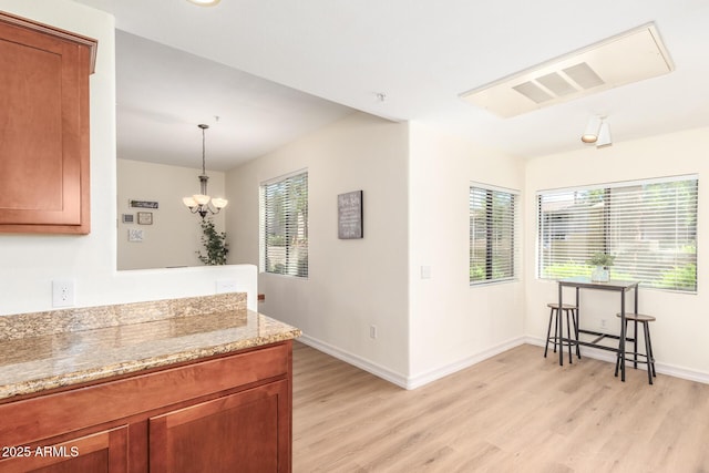 kitchen with light stone counters, brown cabinets, and light wood-style flooring