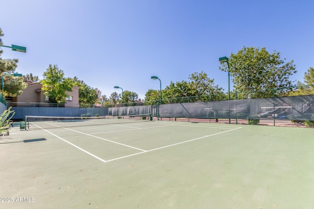 view of tennis court with community basketball court and fence