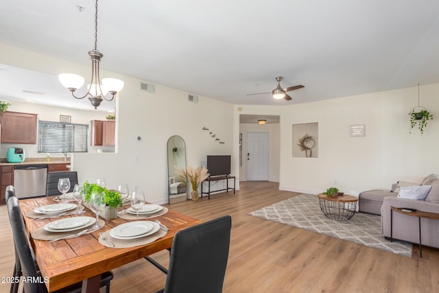 dining area with visible vents, light wood finished floors, and ceiling fan with notable chandelier