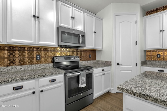 kitchen featuring stainless steel appliances, stone counters, white cabinetry, and tasteful backsplash