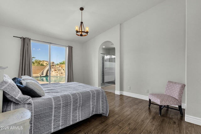 bedroom featuring dark wood-style floors, connected bathroom, arched walkways, baseboards, and a chandelier