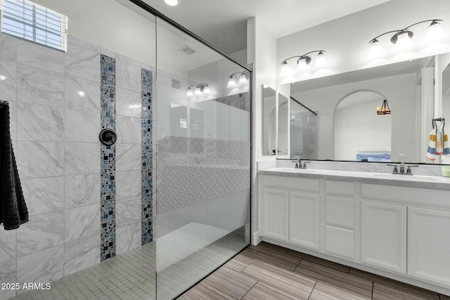 bathroom featuring visible vents, a sink, a walk in shower, and double vanity