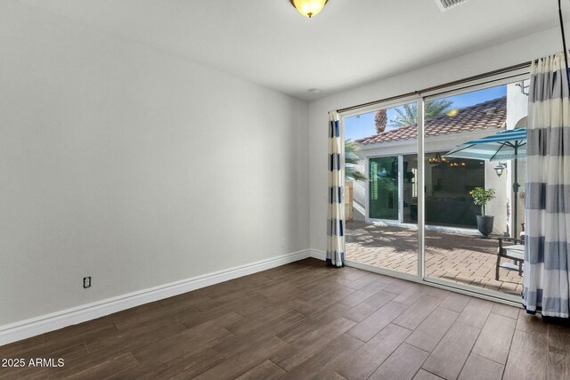 empty room featuring dark wood finished floors, baseboards, and visible vents