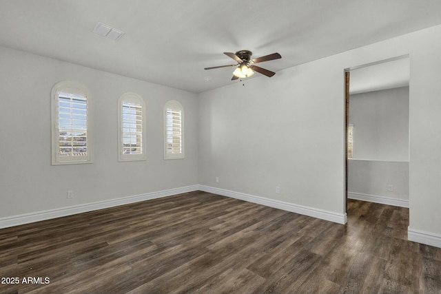 empty room with visible vents, baseboards, dark wood-style floors, and ceiling fan