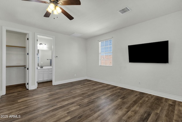unfurnished bedroom featuring a spacious closet, baseboards, visible vents, and dark wood-style floors