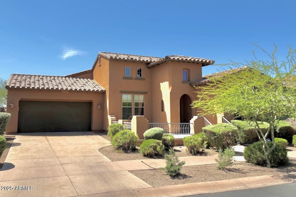mediterranean / spanish home featuring a garage, a tiled roof, stucco siding, and driveway