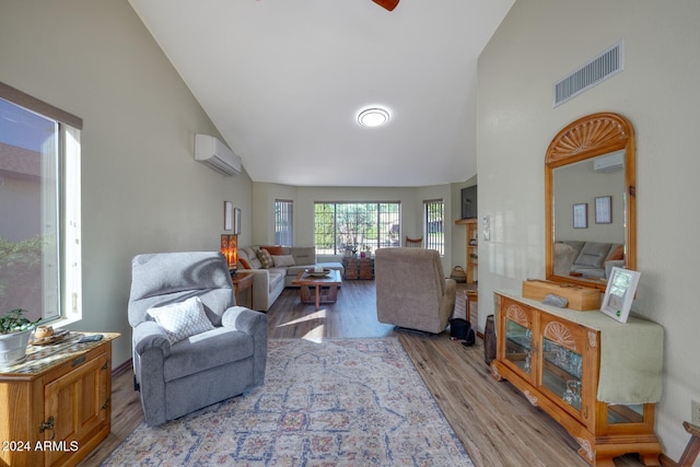 living room with an AC wall unit, high vaulted ceiling, and light hardwood / wood-style flooring