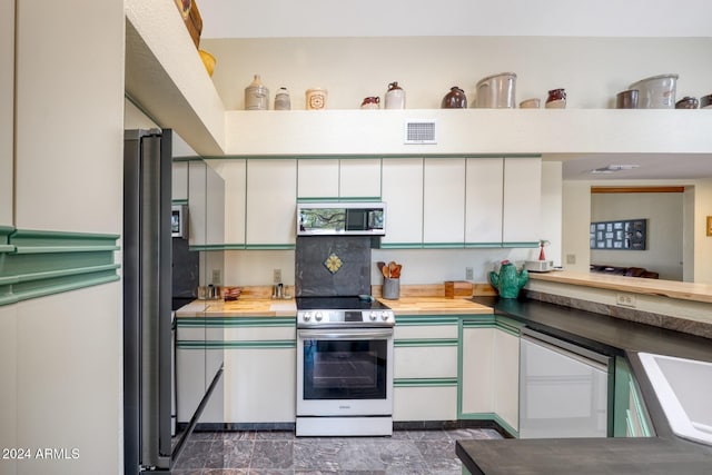 kitchen with wood counters, decorative backsplash, white cabinets, and appliances with stainless steel finishes