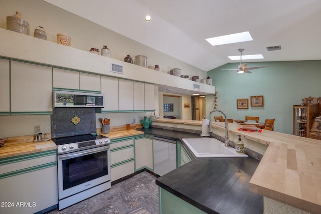 kitchen with vaulted ceiling with skylight, wood counters, kitchen peninsula, and appliances with stainless steel finishes