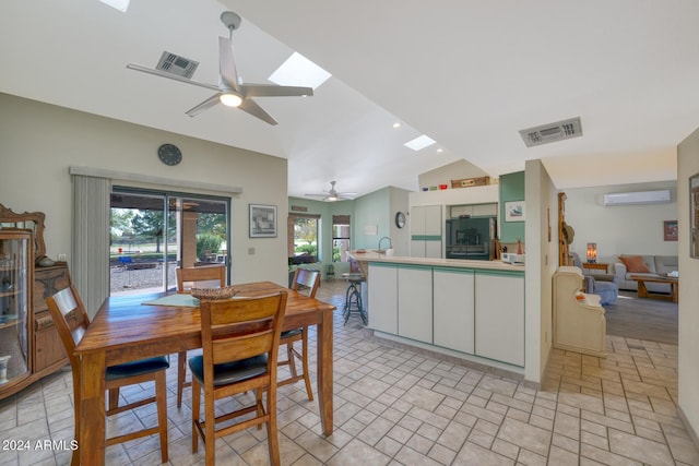 dining area featuring a wall unit AC, ceiling fan, and vaulted ceiling with skylight