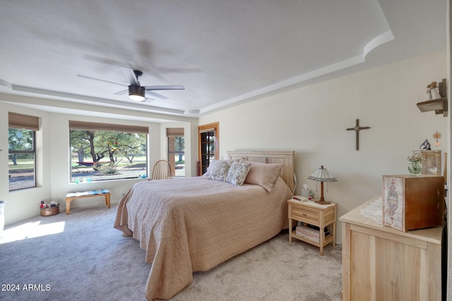 carpeted bedroom featuring ceiling fan and a tray ceiling