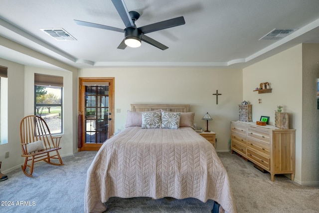 bedroom with a raised ceiling, ceiling fan, and light carpet