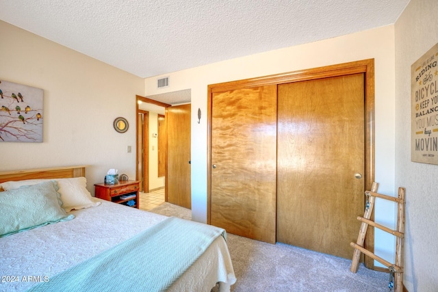 carpeted bedroom featuring a textured ceiling and a closet