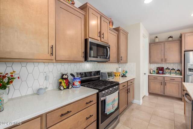 kitchen with light stone counters, appliances with stainless steel finishes, light tile patterned flooring, and decorative backsplash