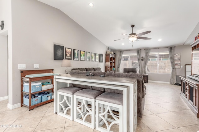 kitchen with ceiling fan, lofted ceiling, a kitchen bar, and light tile patterned floors