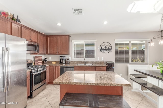 kitchen with sink, hanging light fixtures, stainless steel appliances, and a center island