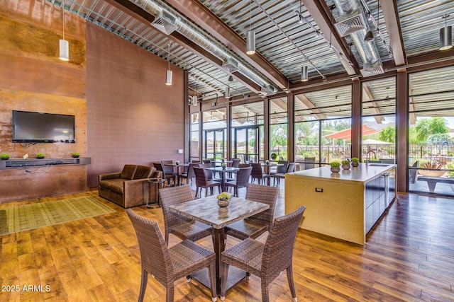 dining space featuring expansive windows, a towering ceiling, and hardwood / wood-style floors