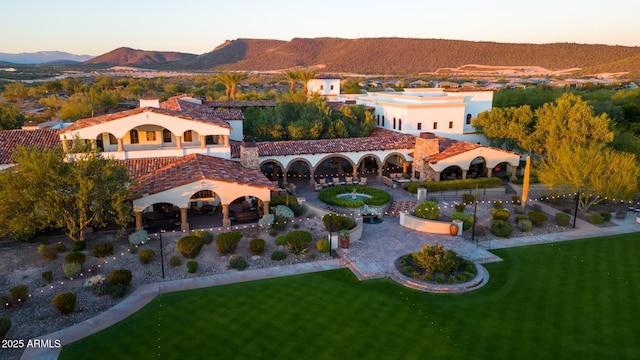 exterior space with a patio, a balcony, a chimney, a mountain view, and a yard