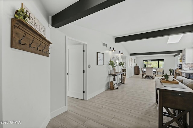 hallway featuring light hardwood / wood-style floors and vaulted ceiling with beams