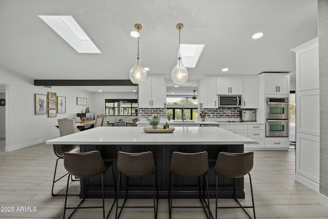 kitchen with white cabinets, appliances with stainless steel finishes, a skylight, and a kitchen island