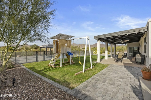 view of play area with a lawn, a patio area, and a mountain view