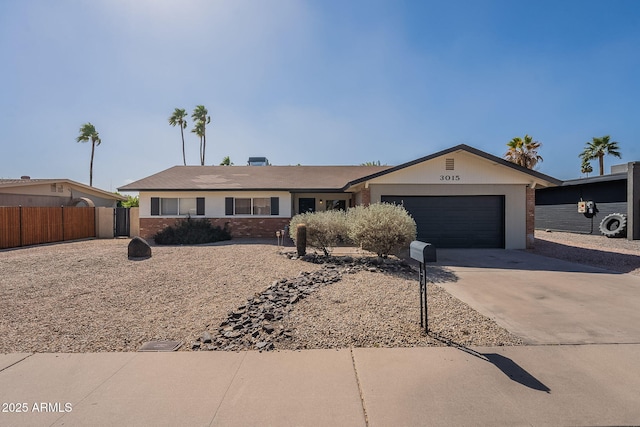 ranch-style house featuring a garage, brick siding, concrete driveway, and fence