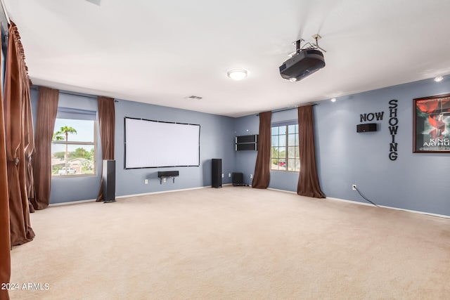 cinema room with light carpet and a wealth of natural light