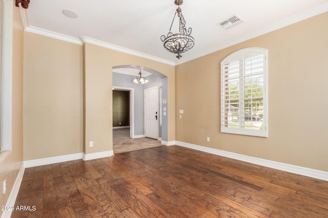 empty room featuring hardwood / wood-style flooring, crown molding, and a notable chandelier