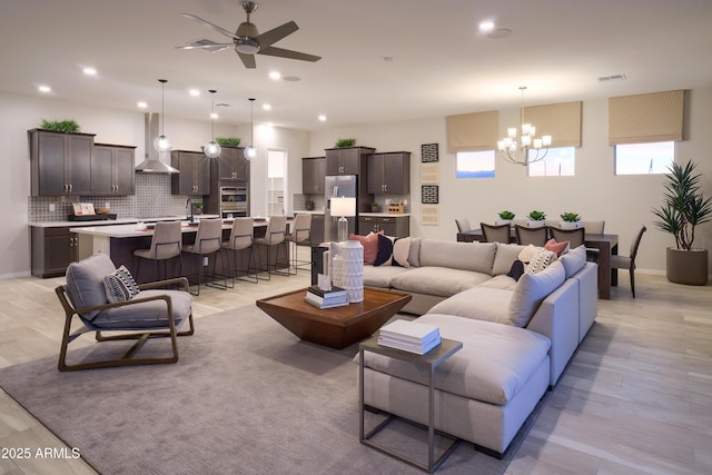 living room featuring sink, ceiling fan with notable chandelier, and light wood-type flooring