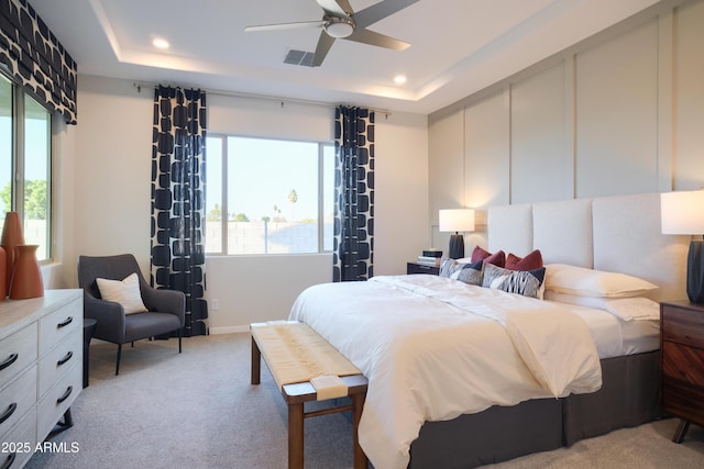 carpeted bedroom featuring ceiling fan and a raised ceiling