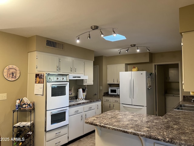 kitchen with sink, white cabinets, white appliances, and kitchen peninsula