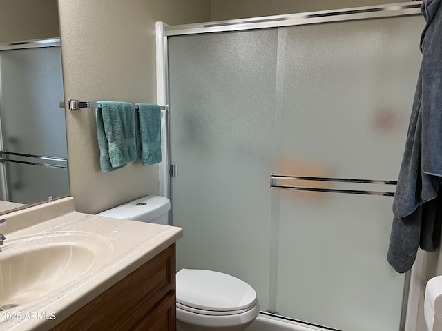 bathroom featuring vanity, a shower with door, and toilet