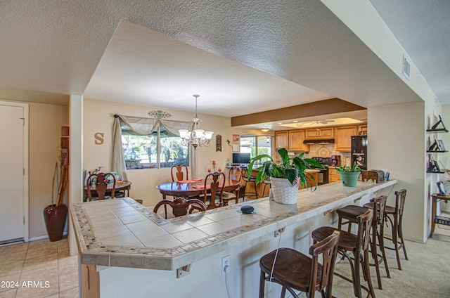 kitchen featuring black fridge, hanging light fixtures, a healthy amount of sunlight, and a breakfast bar