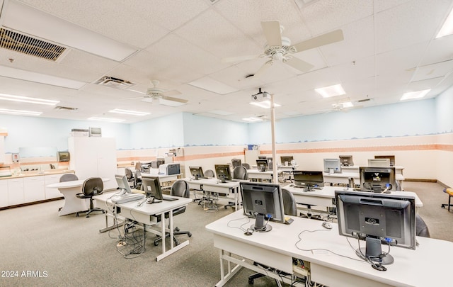 exercise room featuring ceiling fan, light carpet, and a drop ceiling