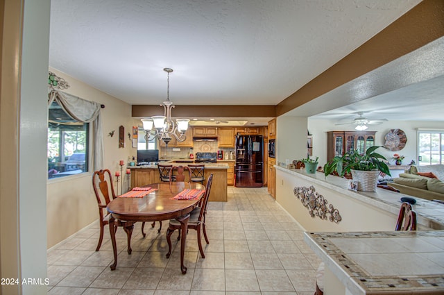 tiled dining area with ceiling fan with notable chandelier and a textured ceiling