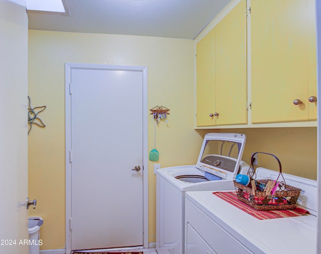 laundry area with cabinets, a skylight, and washing machine and clothes dryer