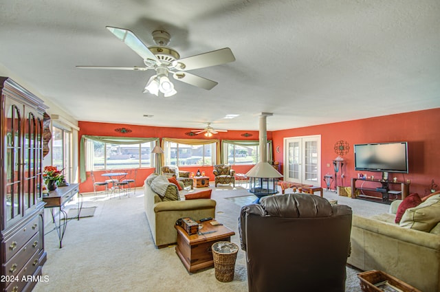 living room featuring ceiling fan, a textured ceiling, light carpet, and ornate columns